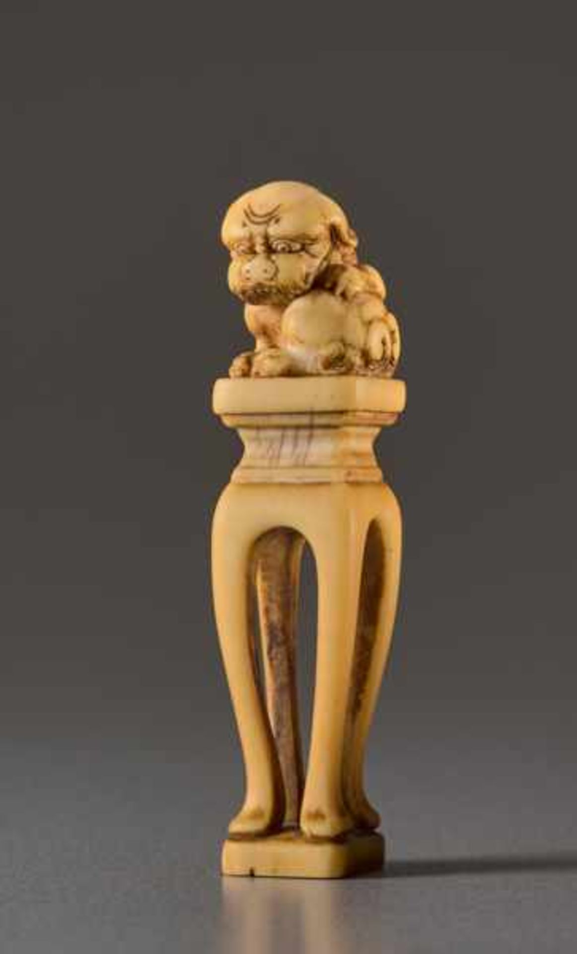 AN IVORY NETSUKE OF A SHISHI ON A PEDESTAL Ivory netsuke. Japan, 19th centuryA very unusually shaped