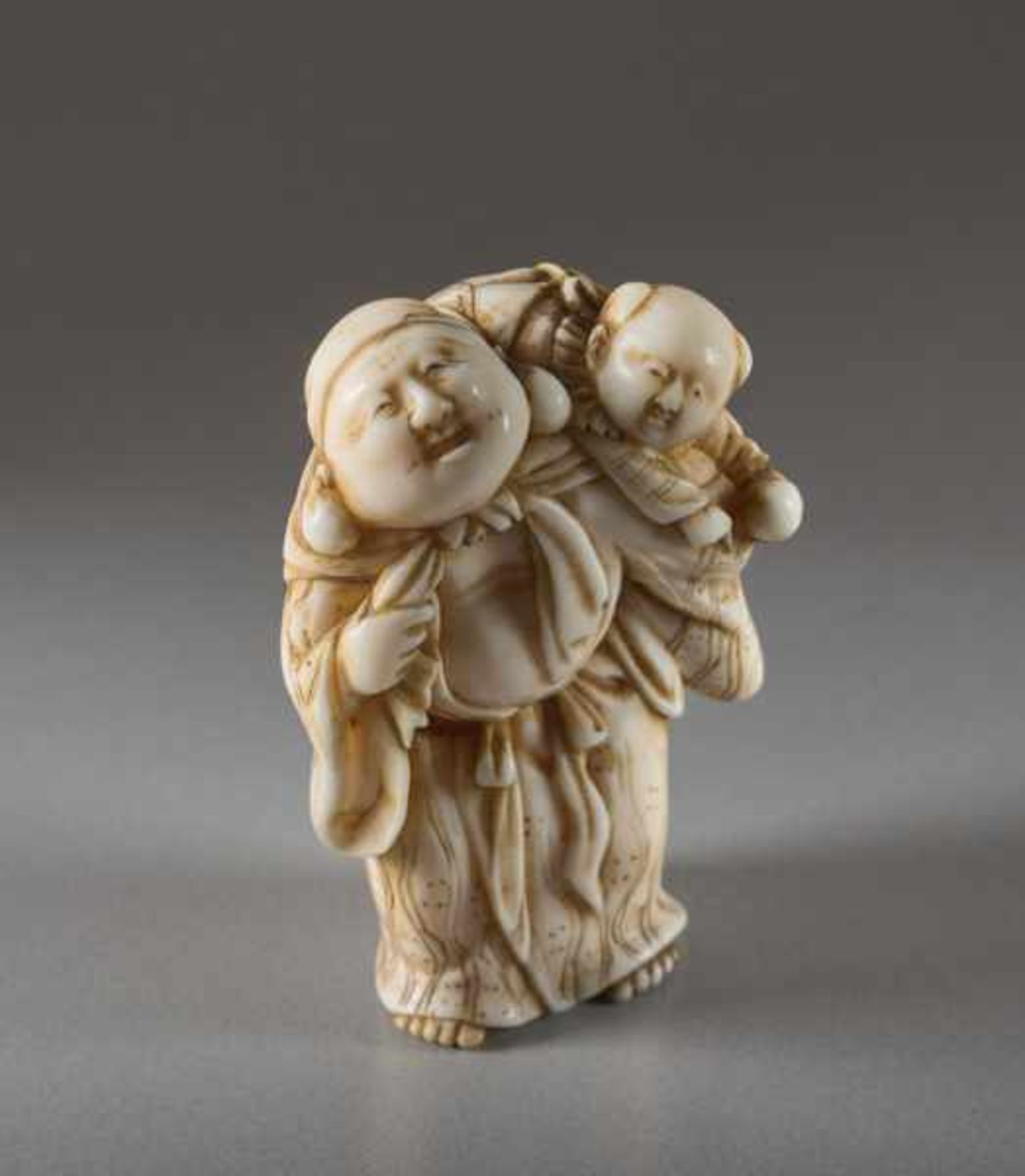 AN IVORY NETSUKE OF HOTEI WITH KARAKO Ivory netsuke. Japan, early 19th centuryA very lively