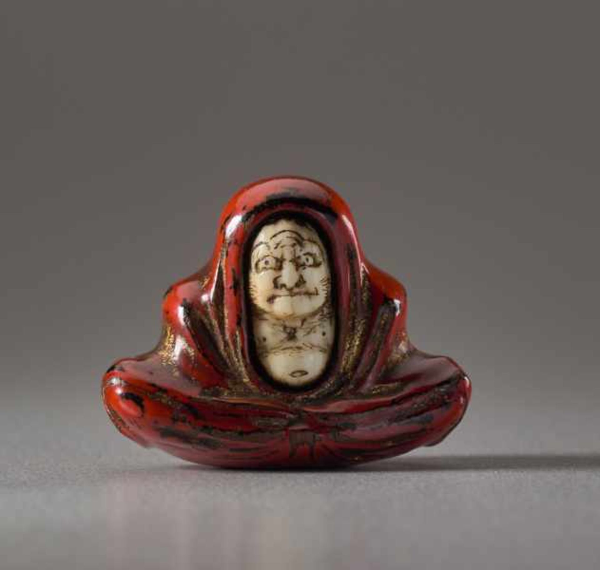 A LACQUERED WOOD AND IVORY NETSUKE OF DARUMA Wood, ivory and lacquer netsuke. Japan, 19th