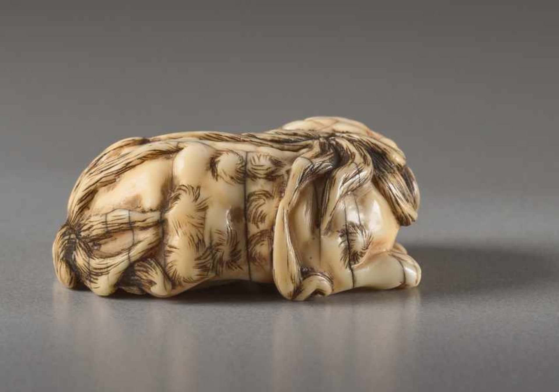 AN IVORY NETSUKE OF A RECUMBENT SHISHI Ivory netsuke. Japan, 19th centuryThis work features all - Image 4 of 5