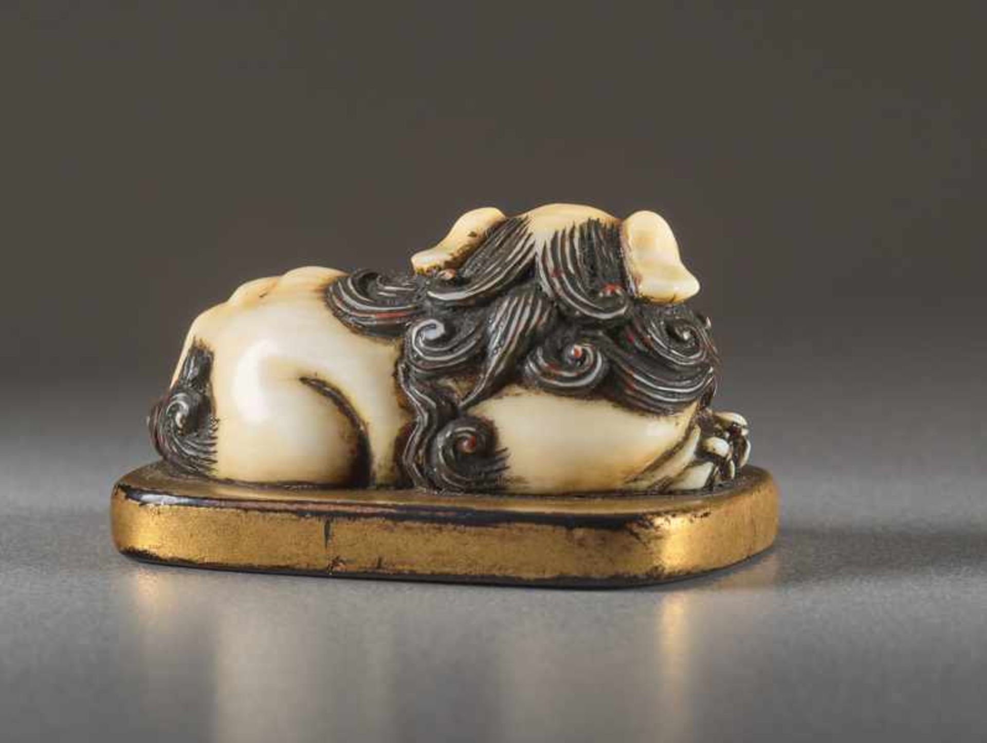 AN IVORY AND LACQUER NETSUKE OF A RECUMBENT SHISHI ON MAT Ivory netsuke with gold lacquer. Japan, - Image 3 of 5