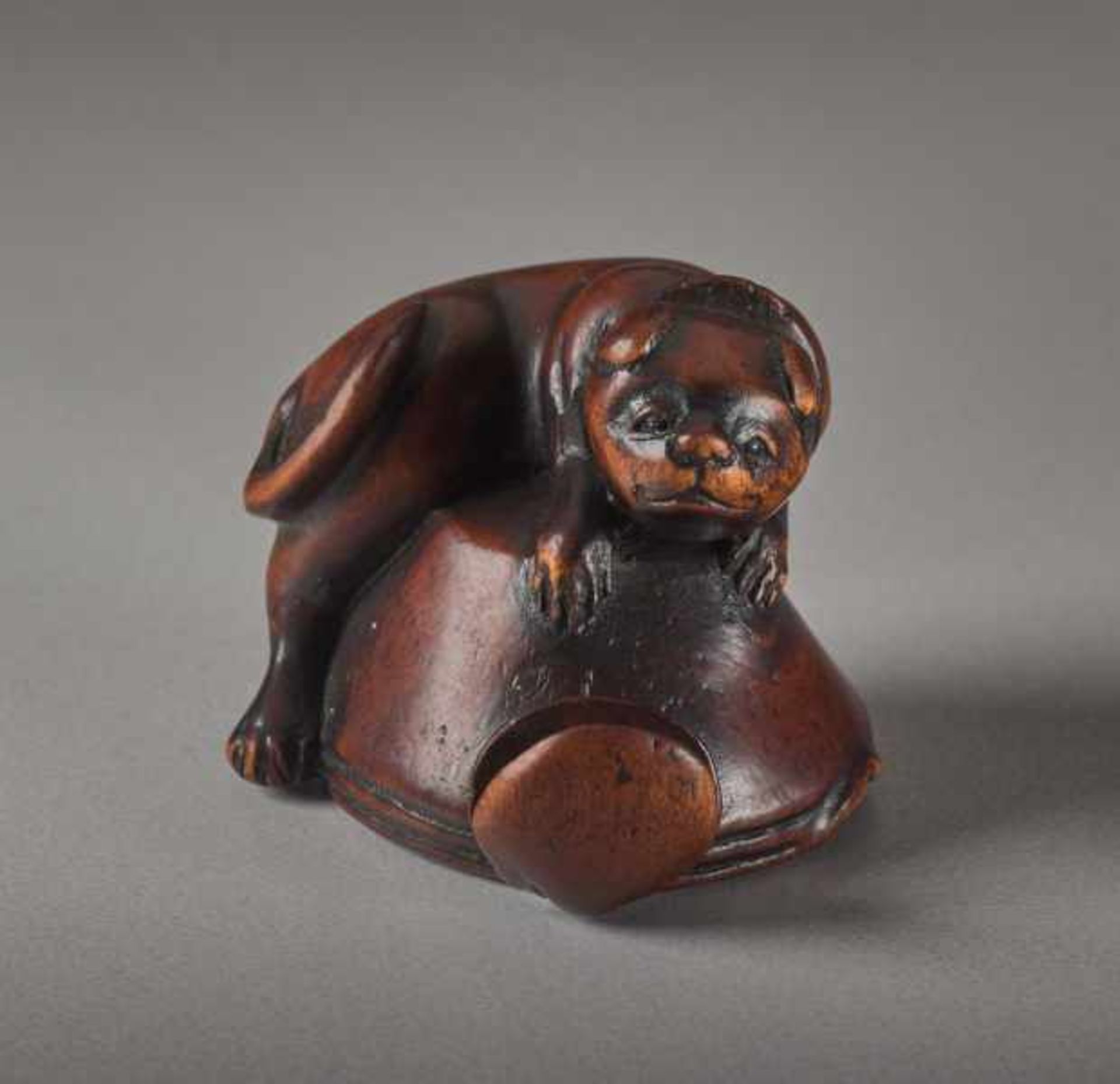 A WOOD NETSUKE OF A DOG AND OCTOPUS Wood netsuke. Japan, 19th centuryThe dog is placed on an