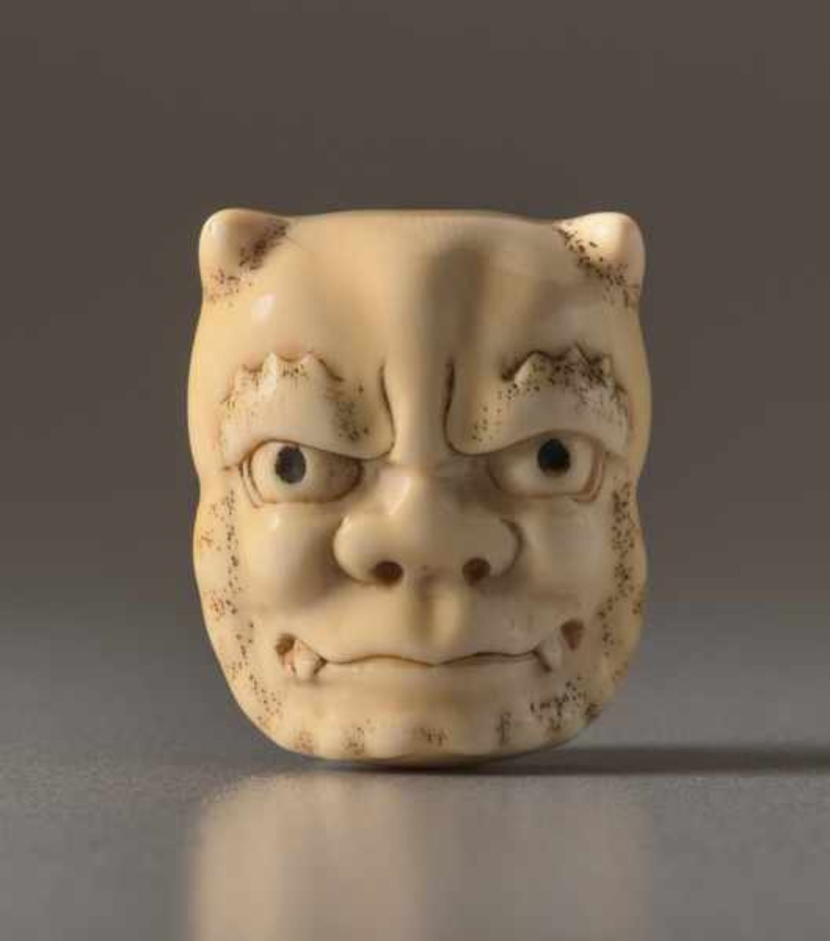 AN IVORY NETSUKE OF A MASK OF AN ONI AND OKAME Ivory netsuke. Japan, 19th centuryThe oni (demon)