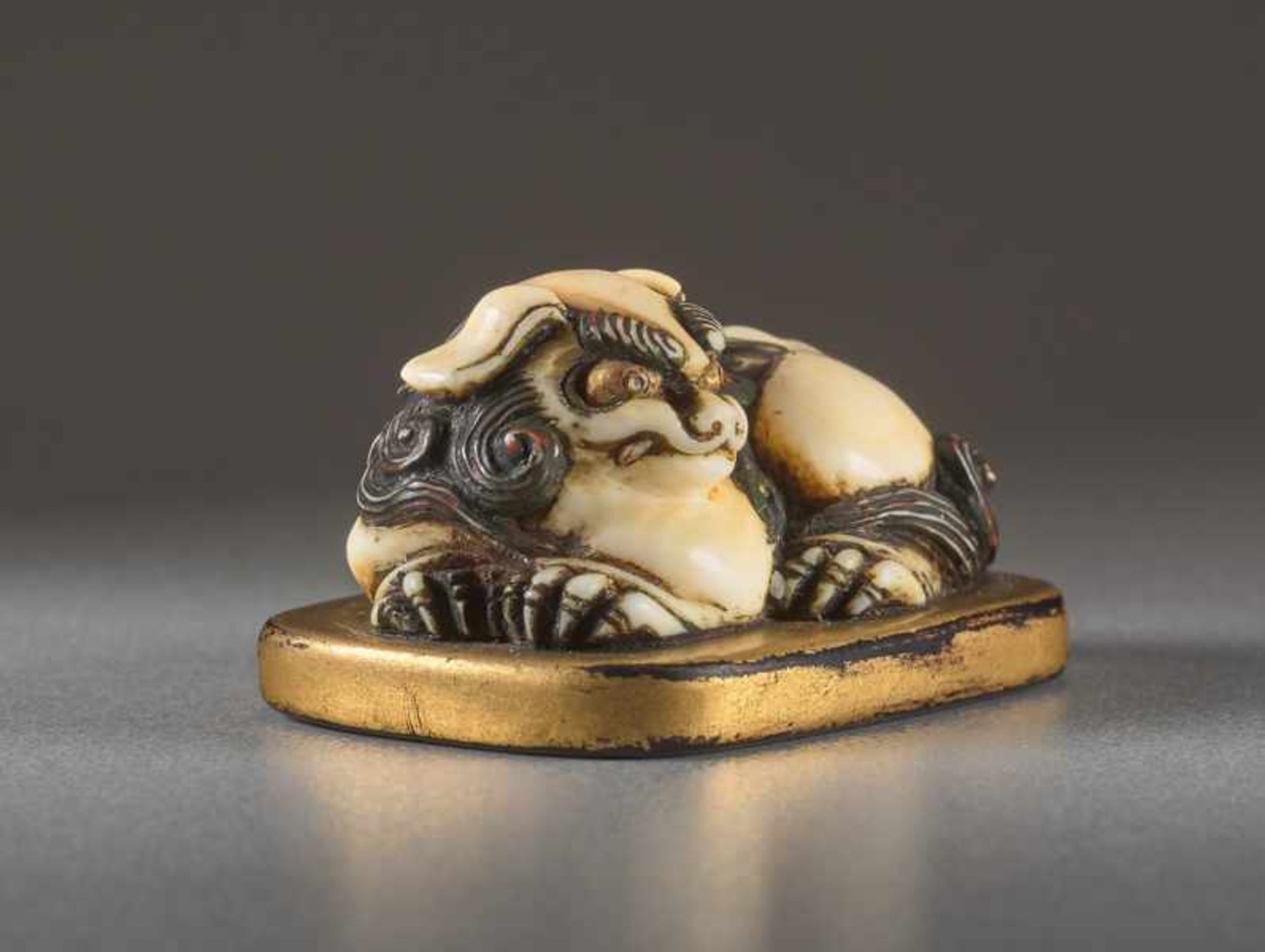 AN IVORY AND LACQUER NETSUKE OF A RECUMBENT SHISHI ON MAT Ivory netsuke with gold lacquer. Japan, - Image 4 of 5