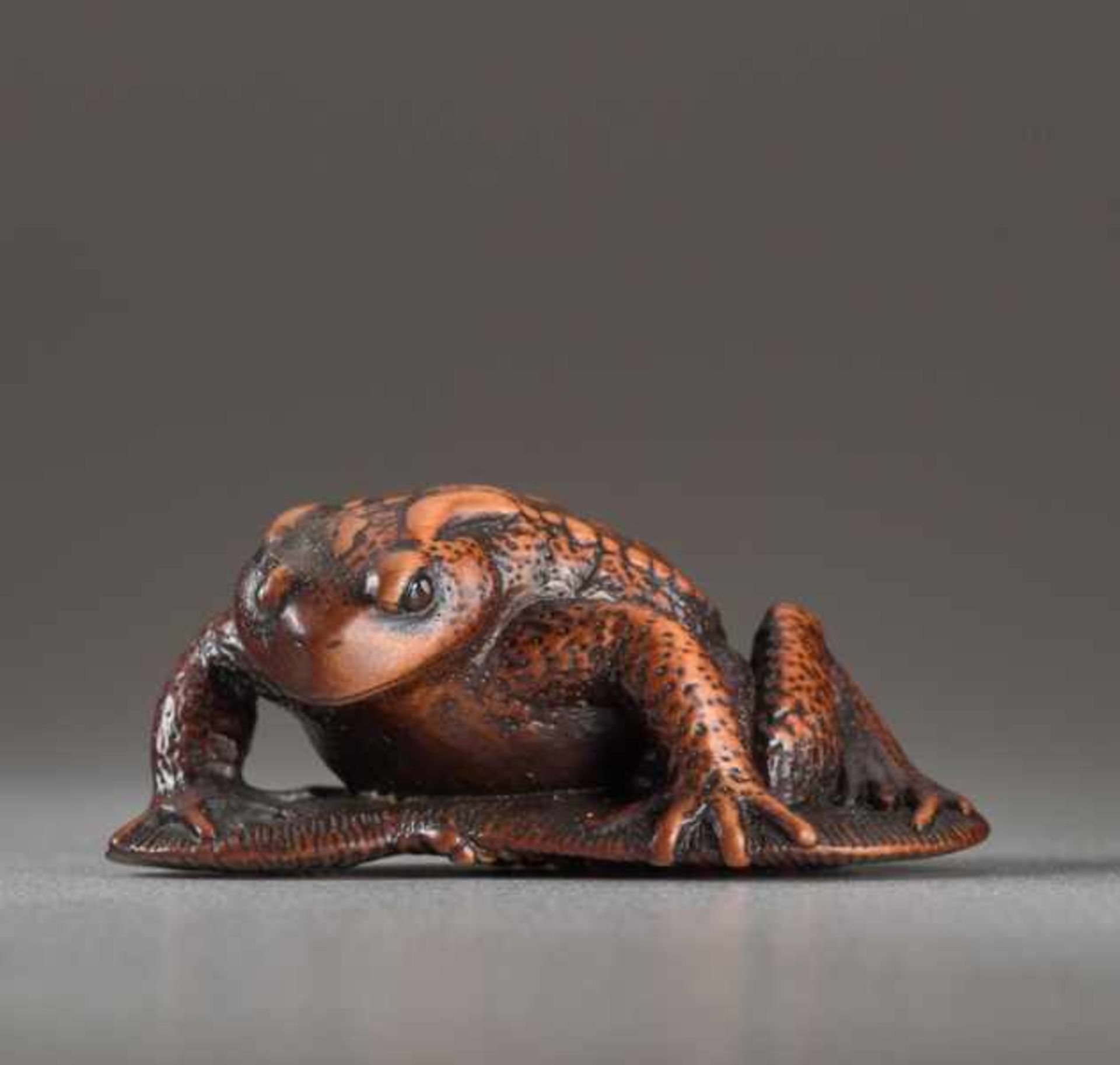 A WOOD NETSUK E BY TANRI OF A TOAD ON A SANDAL Wood netsuke. Japan, 19th centuryThis very finely