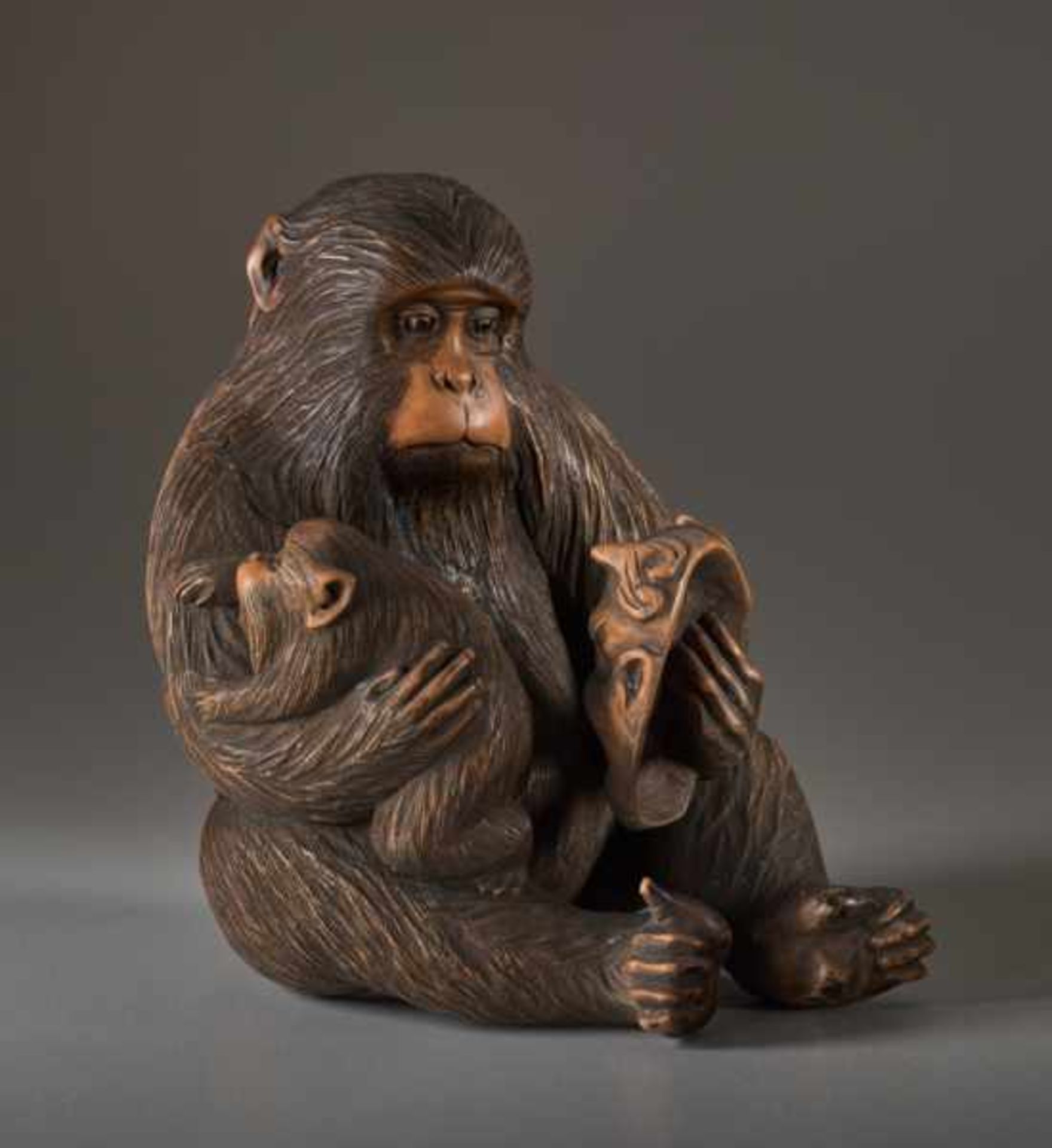 A WOOD OKIMONO BY JIGO OF A MONKEY WITH CHILD AND MASK Wood okimono. Japan, Meiji periodThe monkey