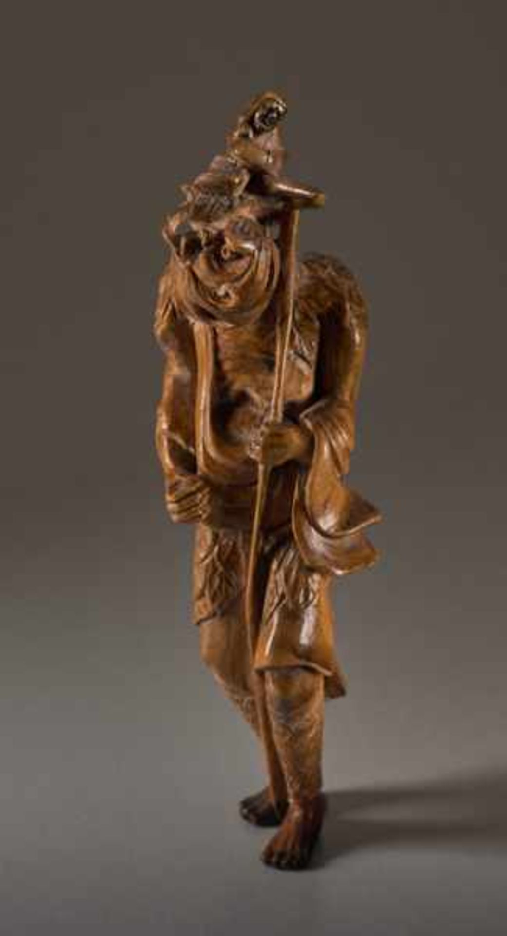 A TALL WOOD NETSUKE OF TEKKAI SENNIN Wood netsuke. Japan, 19th centuryThe immortal with his iron