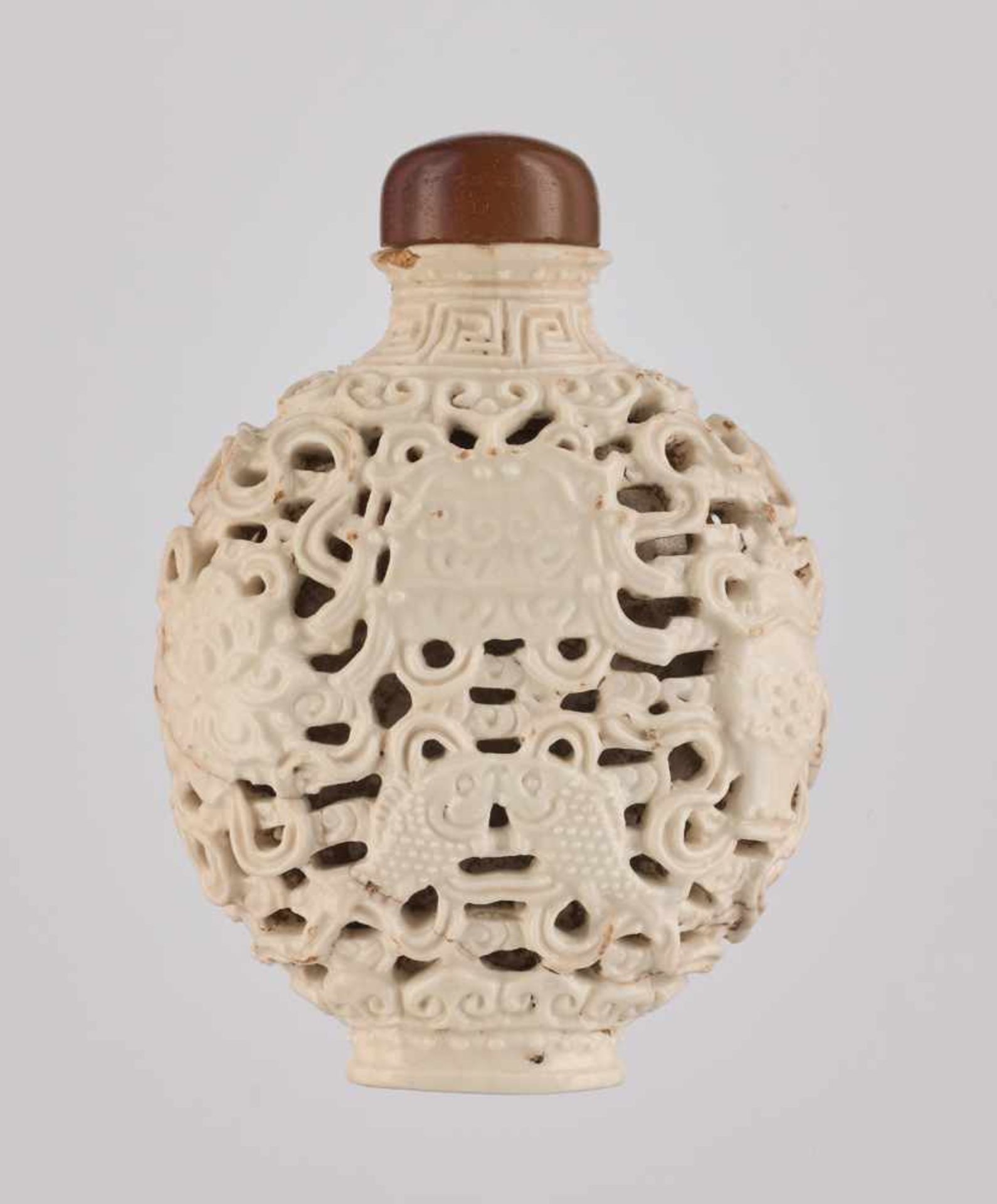 A RETICULATED WHITE PORCELAIN 'BA JIXIANG' SNUFF BOTTLE Crackled creamy-white glaze on molded and