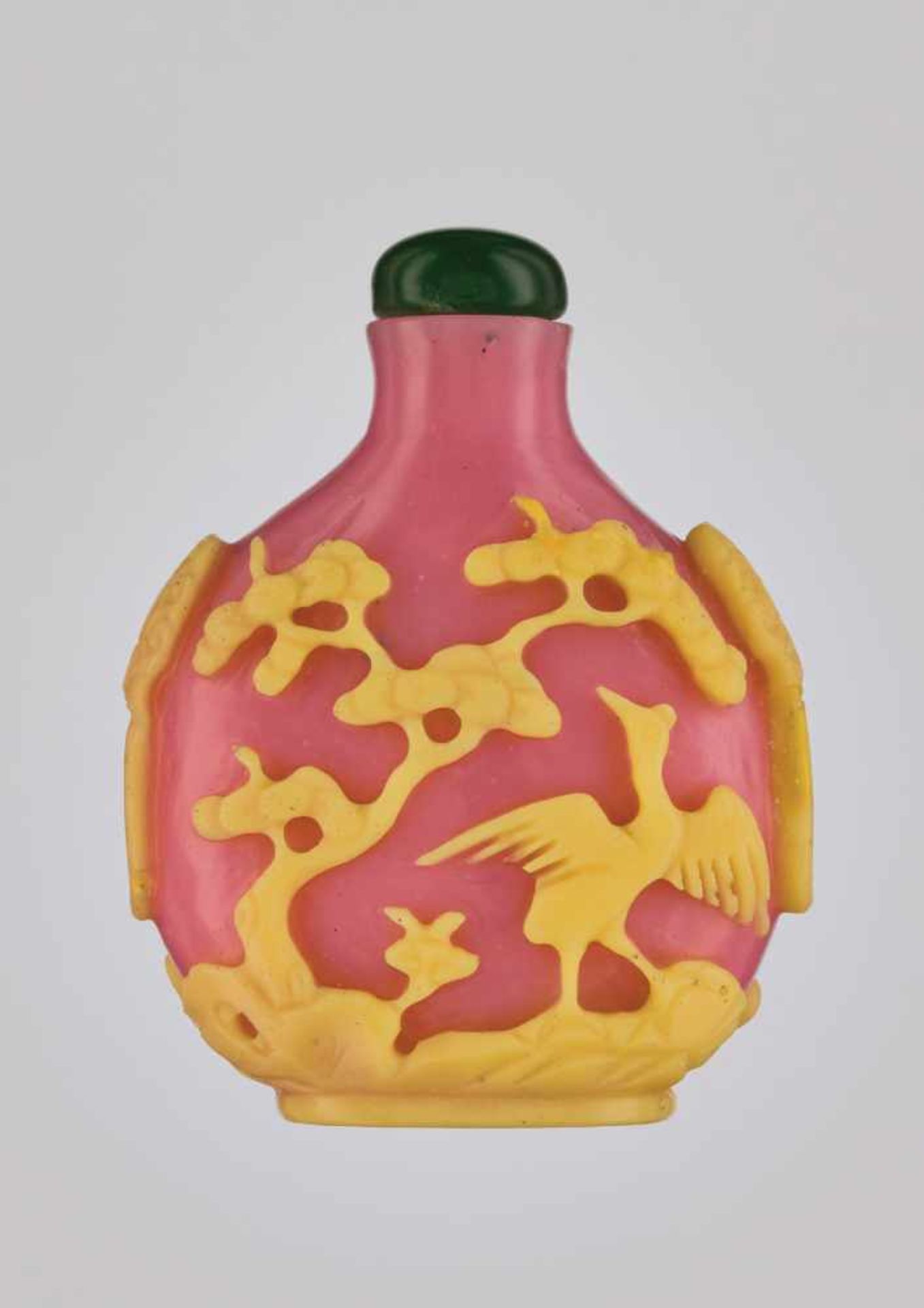 A YELLOW-OVERLAY PINK ‘CRANES & PINES’ GLASS SNUFF BOTTLE Opaque pink glass with carved and