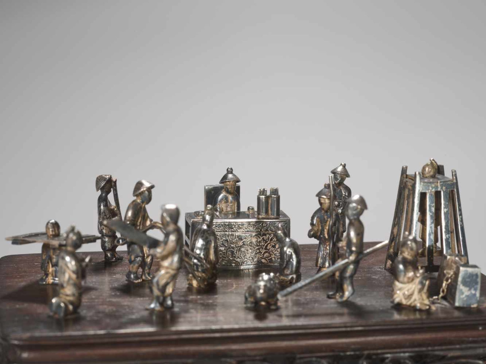 A QING DYNASTY SILVER MINIATURE GROUP ‘MAGISTRATE HOLDING COURT’ Silver and metal, wooden base - Image 2 of 9