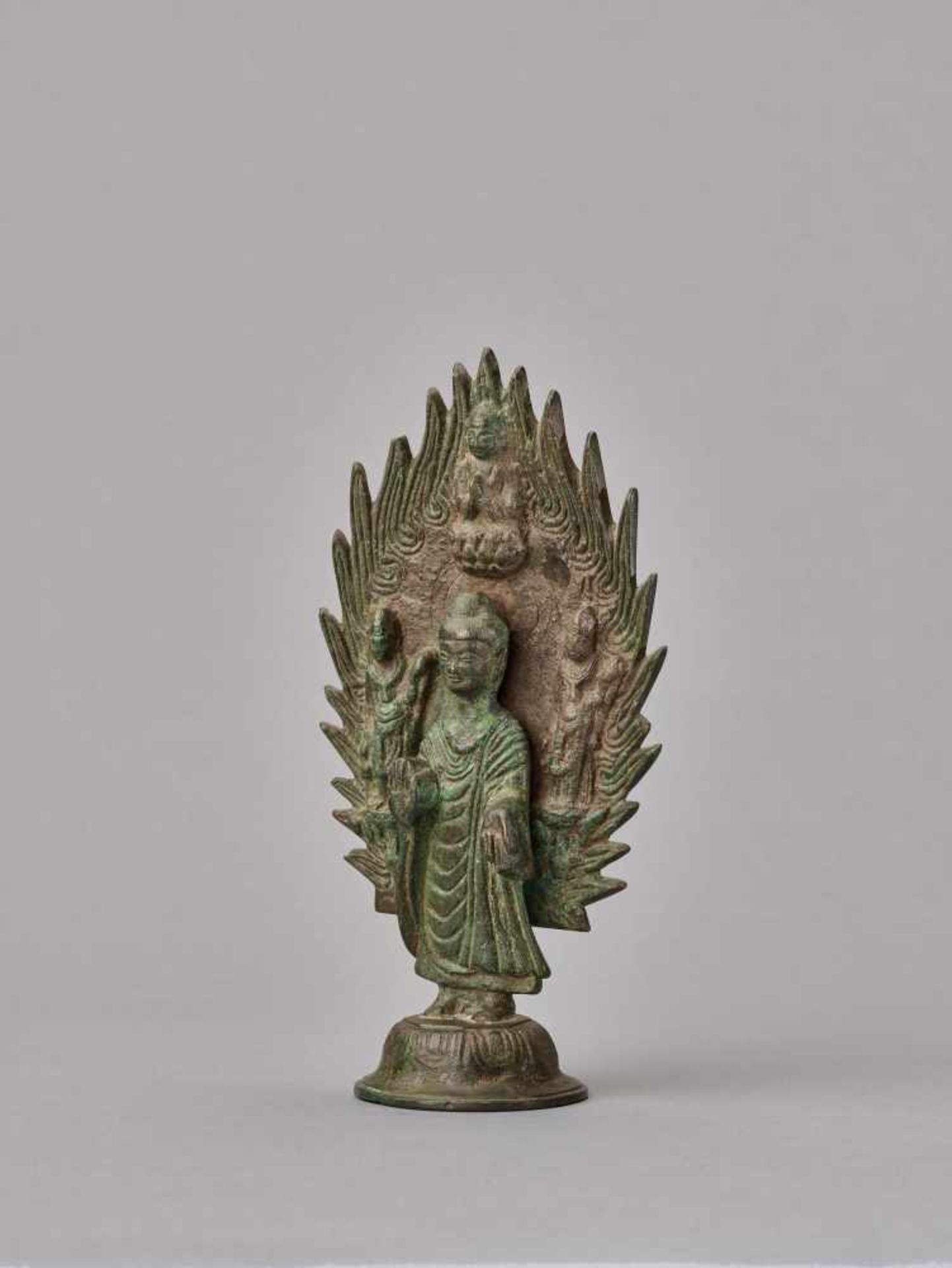 A BRONZE BUDDHA STANDING IN FRONT OF A FLAMING HALO, DATED 571 Cast and incised bronze with a rich