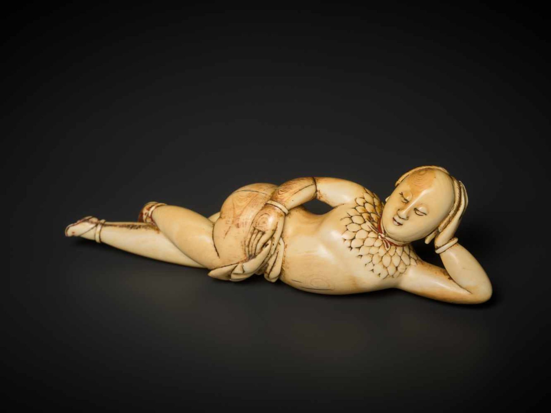 A CARVED 17th CENTURY IVORY FIGURE OF A RECLINING WOMAN Ivory, sparse remains of paintwork. Rosewood