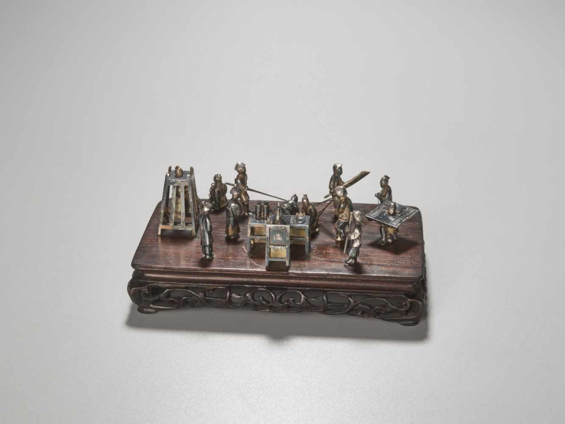 A QING DYNASTY SILVER MINIATURE GROUP ‘MAGISTRATE HOLDING COURT’ Silver and metal, wooden base - Image 9 of 9