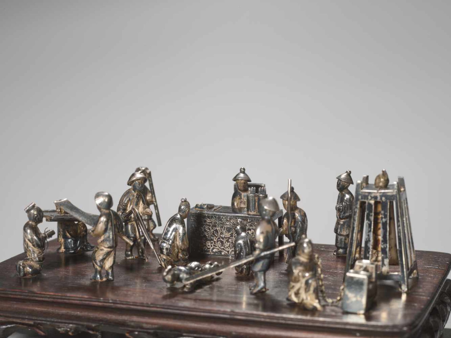 A QING DYNASTY SILVER MINIATURE GROUP ‘MAGISTRATE HOLDING COURT’ Silver and metal, wooden base - Image 5 of 9