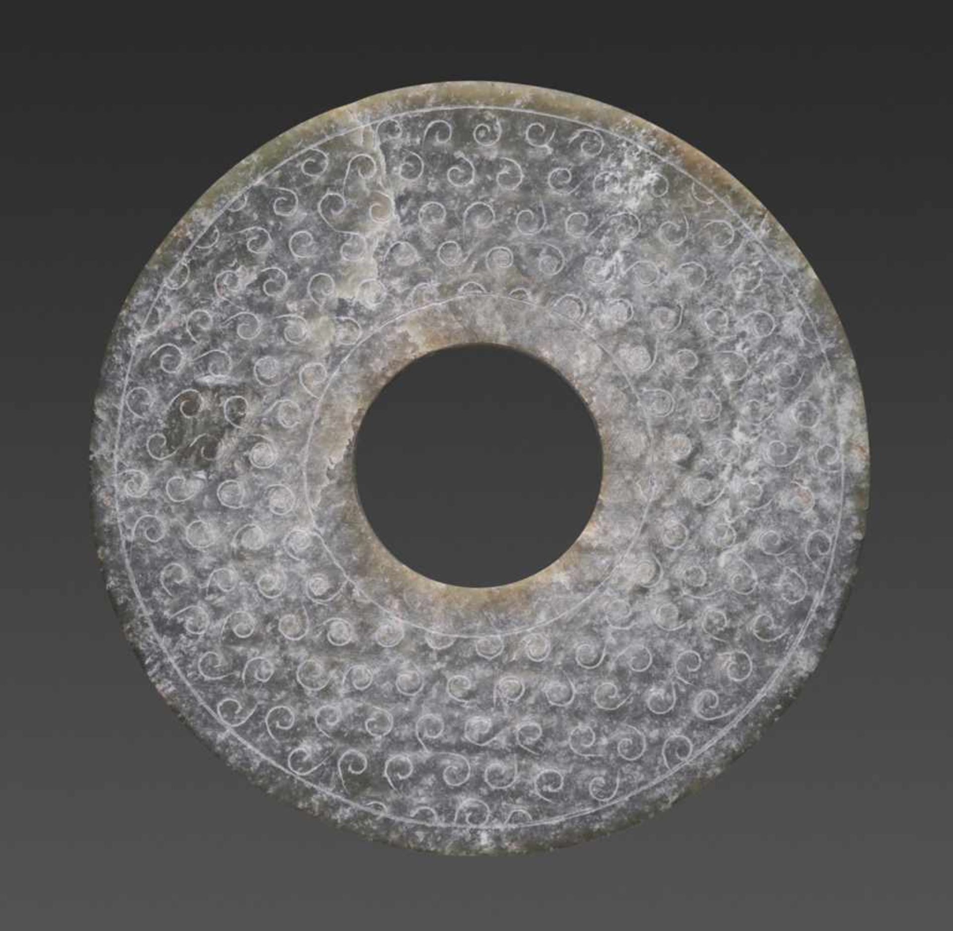 A REFINED CHARCOAL GREY DISC WITH ENGRAVED CURLS Jade. China, Han Dynasty, 2nd century BC 穀紋玉璧 - 漢代,