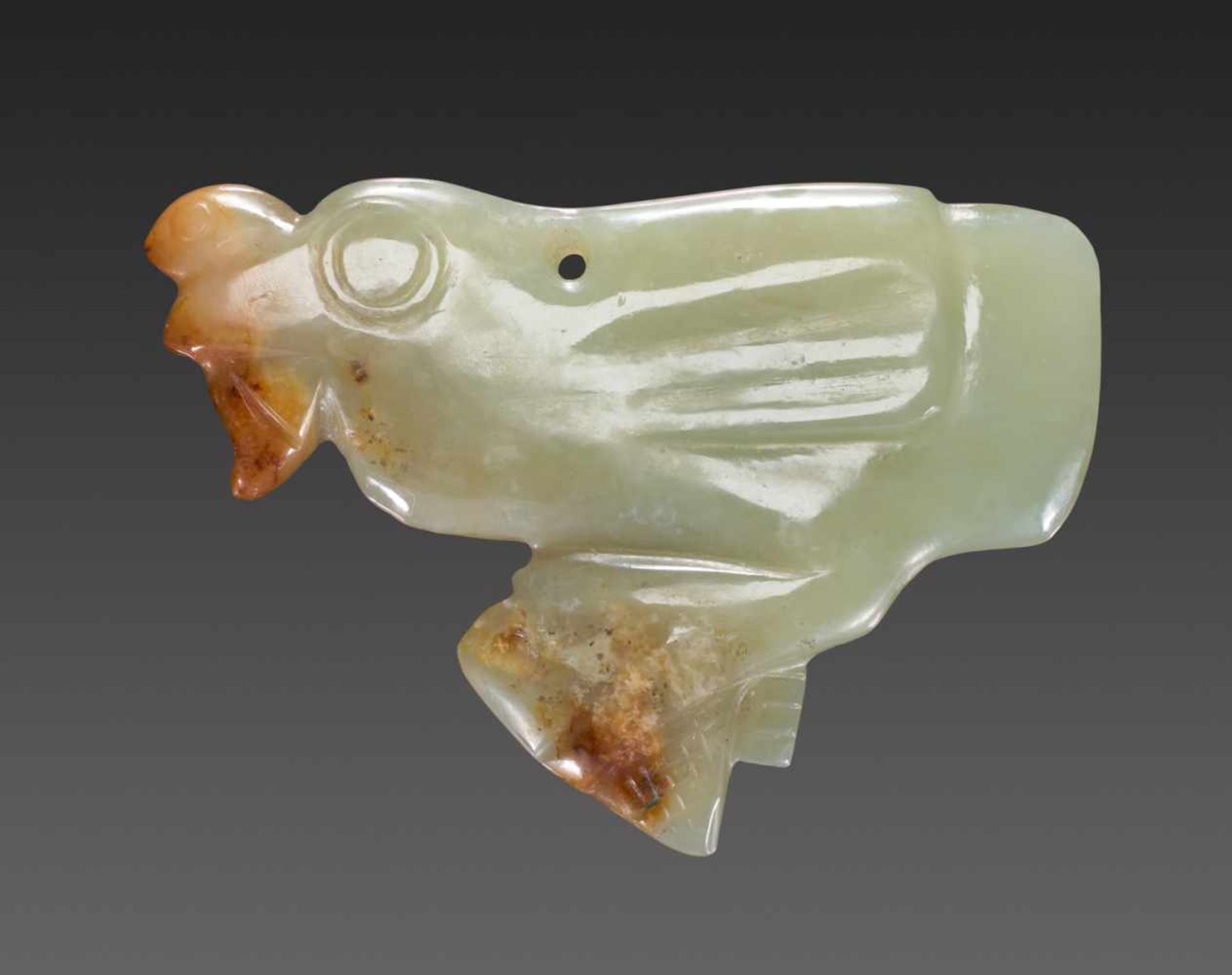 A DELIGHFUL LIGHT GREEN JADE BIRD HOLDING TWO FISH Jade. China, Late Shang, Early Western Zhou, c.