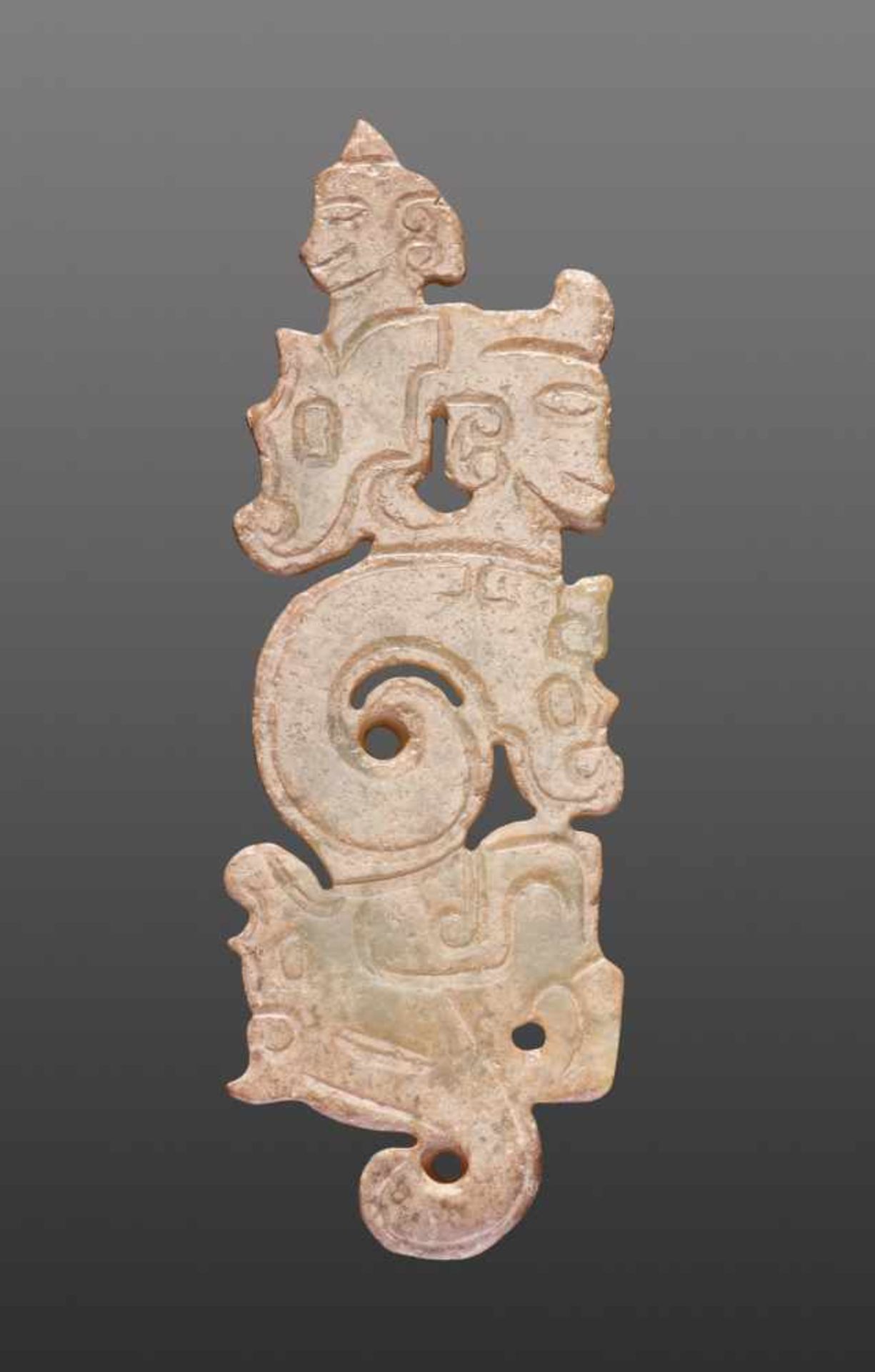 A THIN, FLAT ORNAMENT WITH A COMPOSITE PATTERN OF HUMAN HEADS AND DRAGONS Jade. China, Western Zhou,