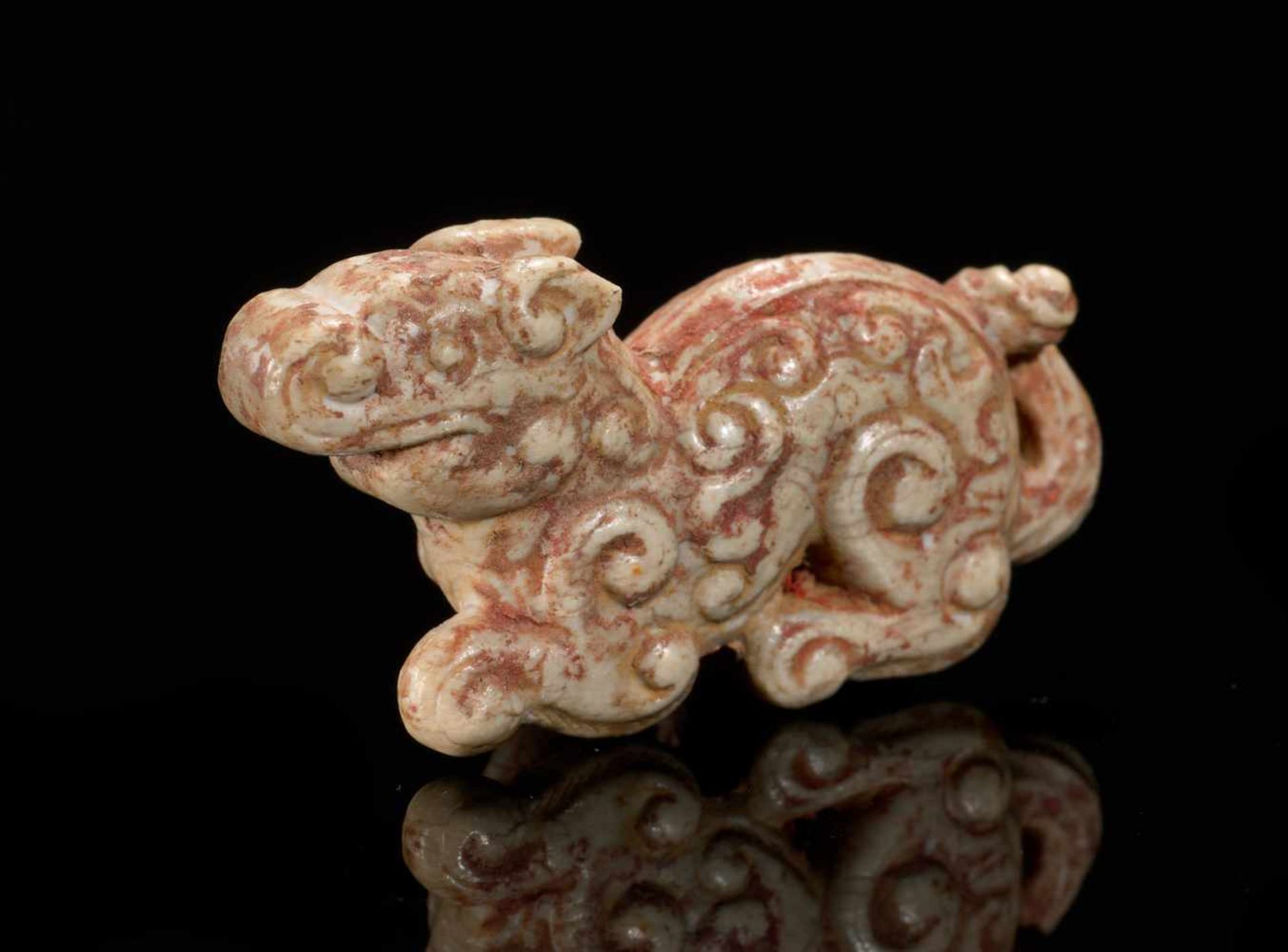 A MINISCULE CROUCHING ANIMAL WITH AN INTRICATE PATTERN OF CARVED CURLS Jade. China, Eastern Zhou,