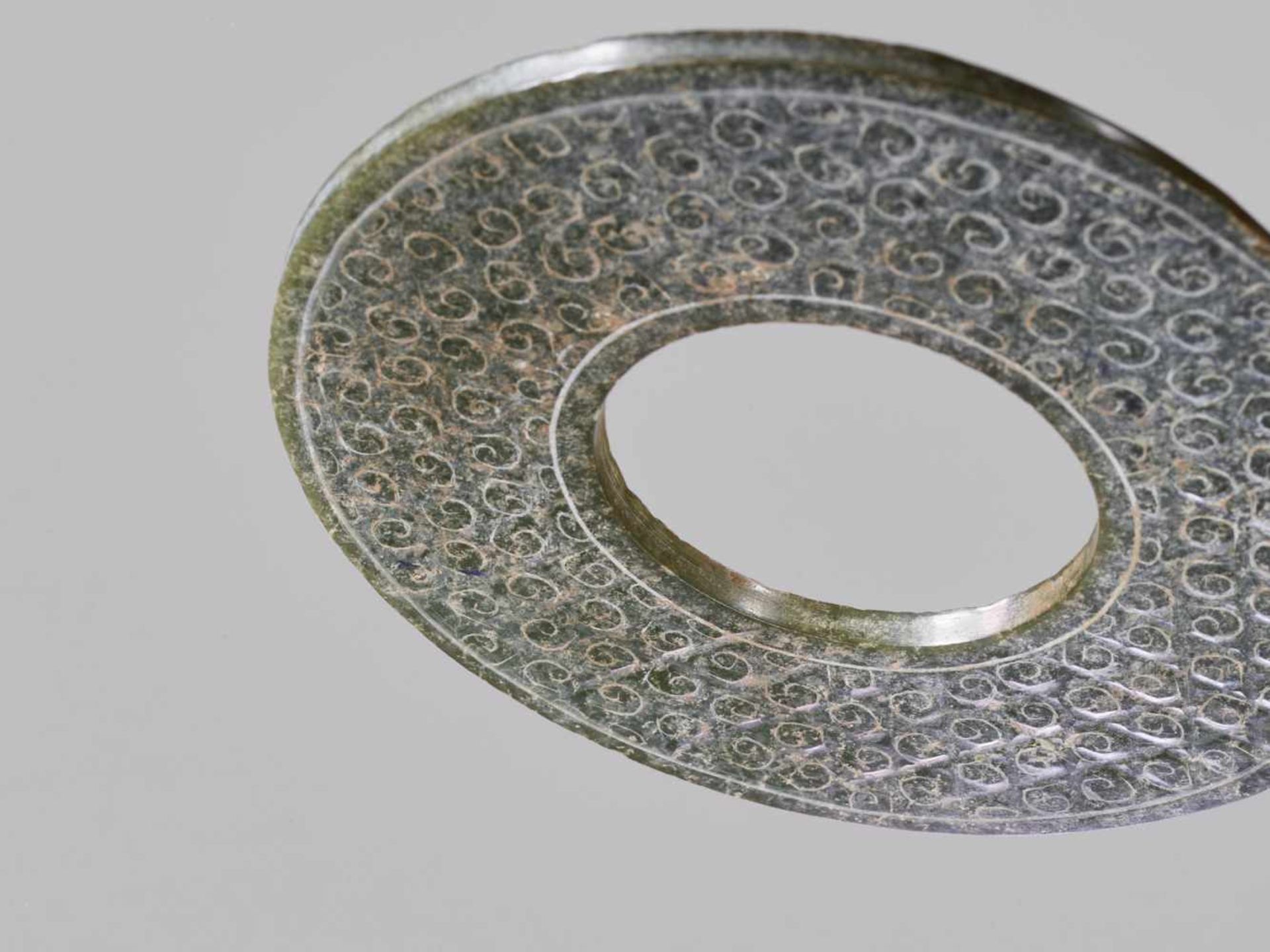 A SHINY GREEN DISC WITH A DELICATE PATTERN OF INCISED SCROLLS Jade. China, Han Dynasty, 2nd - Image 7 of 10