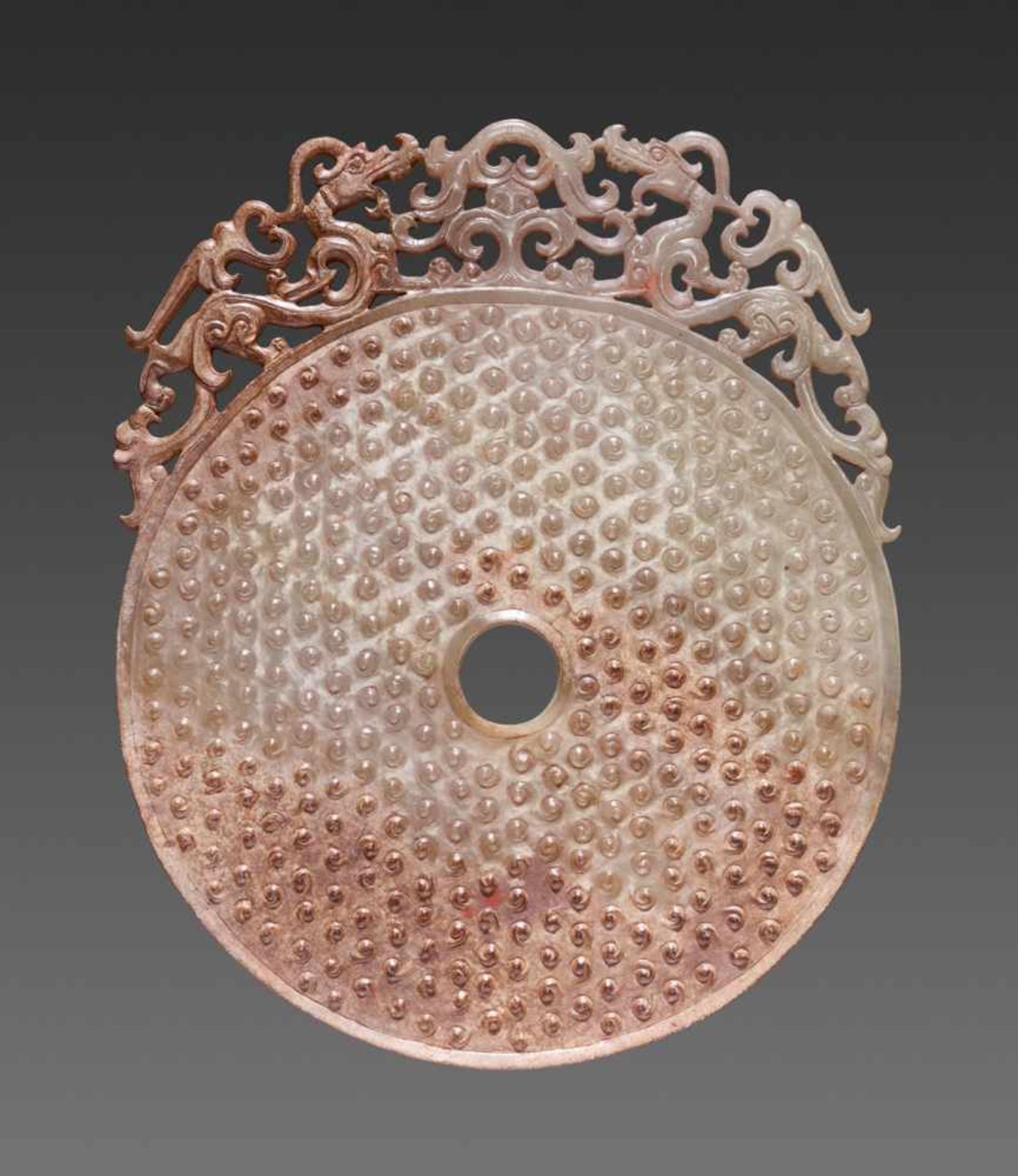 A GORGEOUS DISC IN WHITE JADE CARVED WITH CONFRONTING DRAGONS IN OPENWORK AND A PATTERN OF RAISED