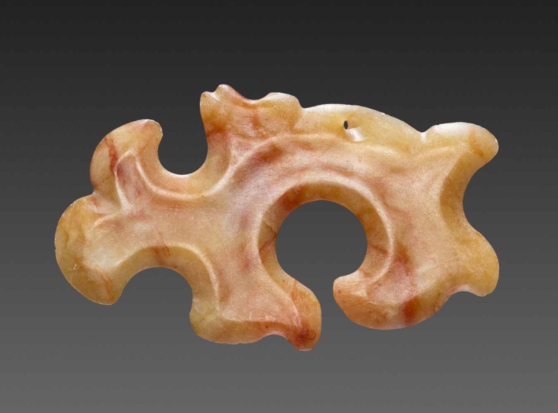 A SMOOTHLY POLISHED ABSTRACT-LOOKING PENDANT OF THE GOUYUN OR “HOOKED-CLOUD” TYPE Jade. China,