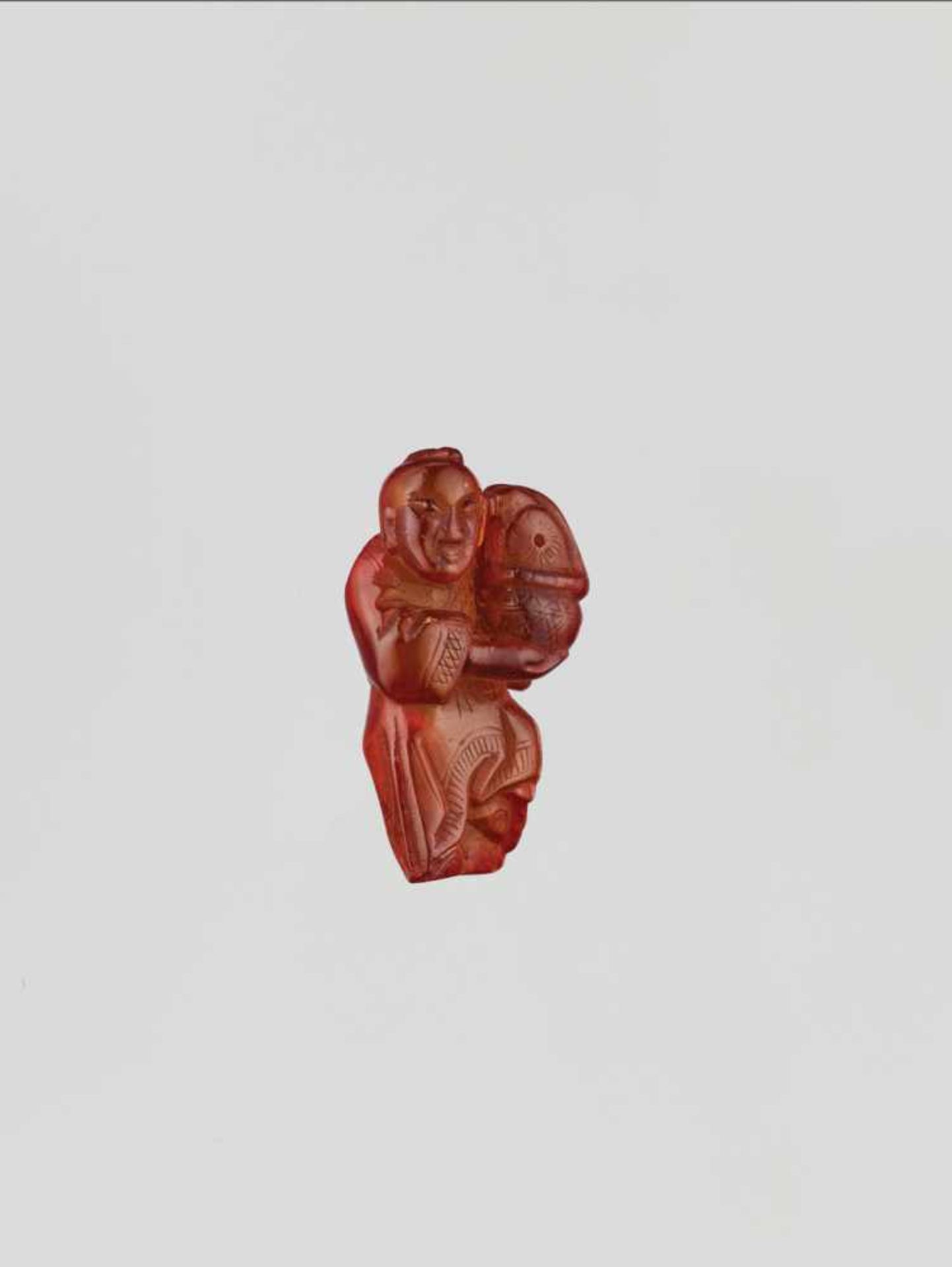 A QING DYNASTY AMBER CARVING OF BOY WITH BASKET Amber of bright orange color and of near translucent