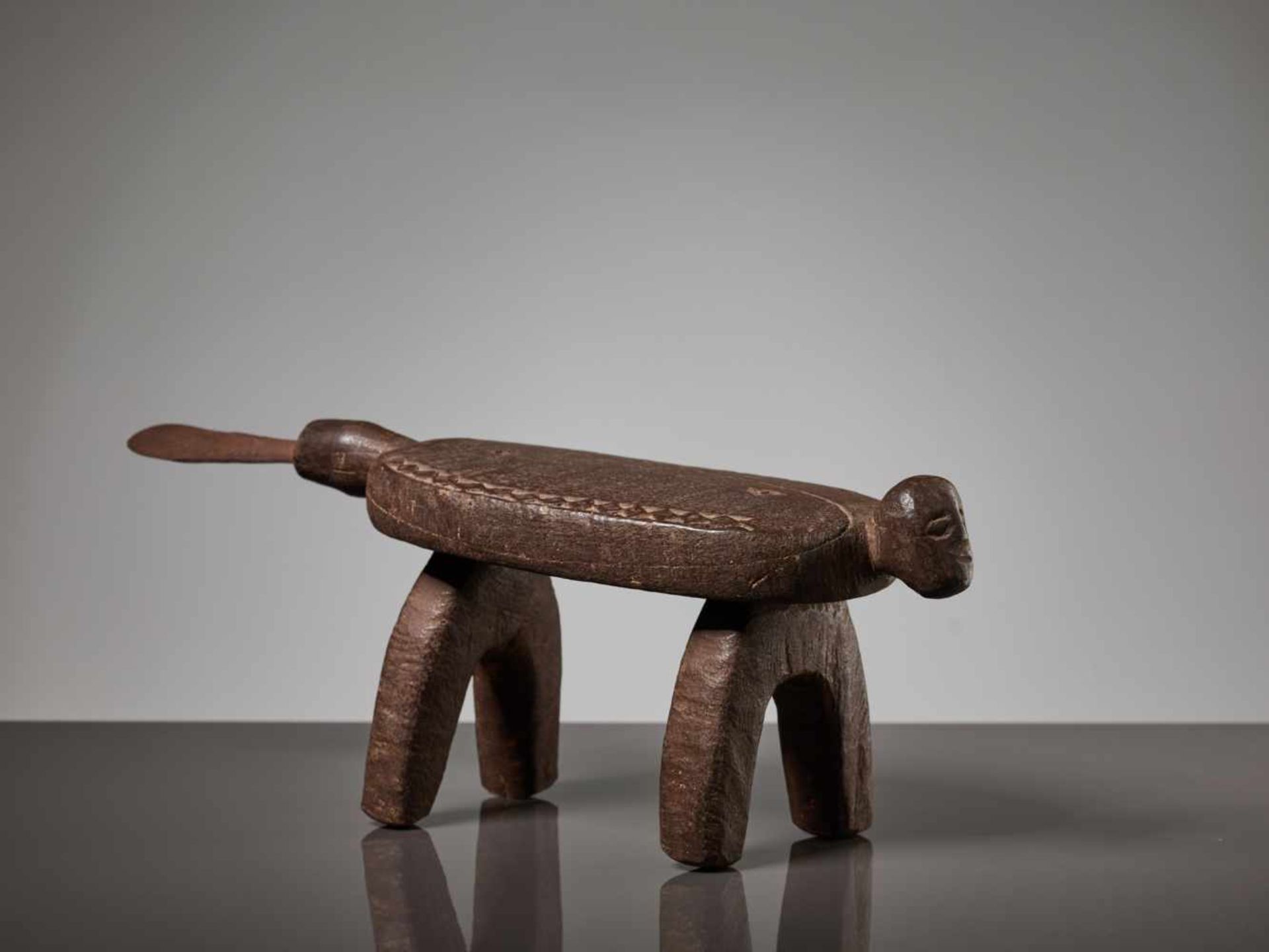 A WOODEN STOOL WITH A HUMAN FACE, BURKINA FASO, LOBI PEOPLEBrown painted wood, iron bladeBurkina