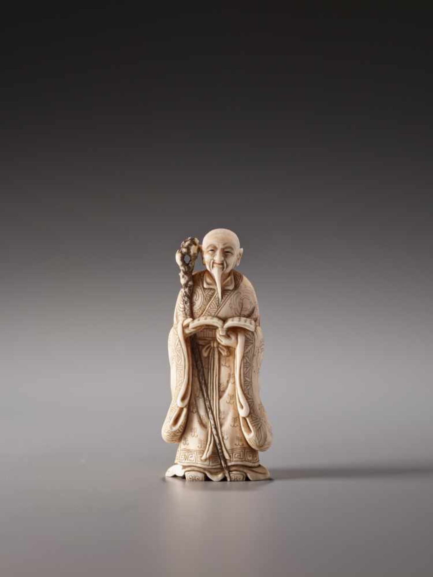 AN IVORY NETSUKE OF A TAOIST SAGE WITH A BOOK AND SAGEMONO BY MEIKEIIvory netsukeJapan, Kyoto20th