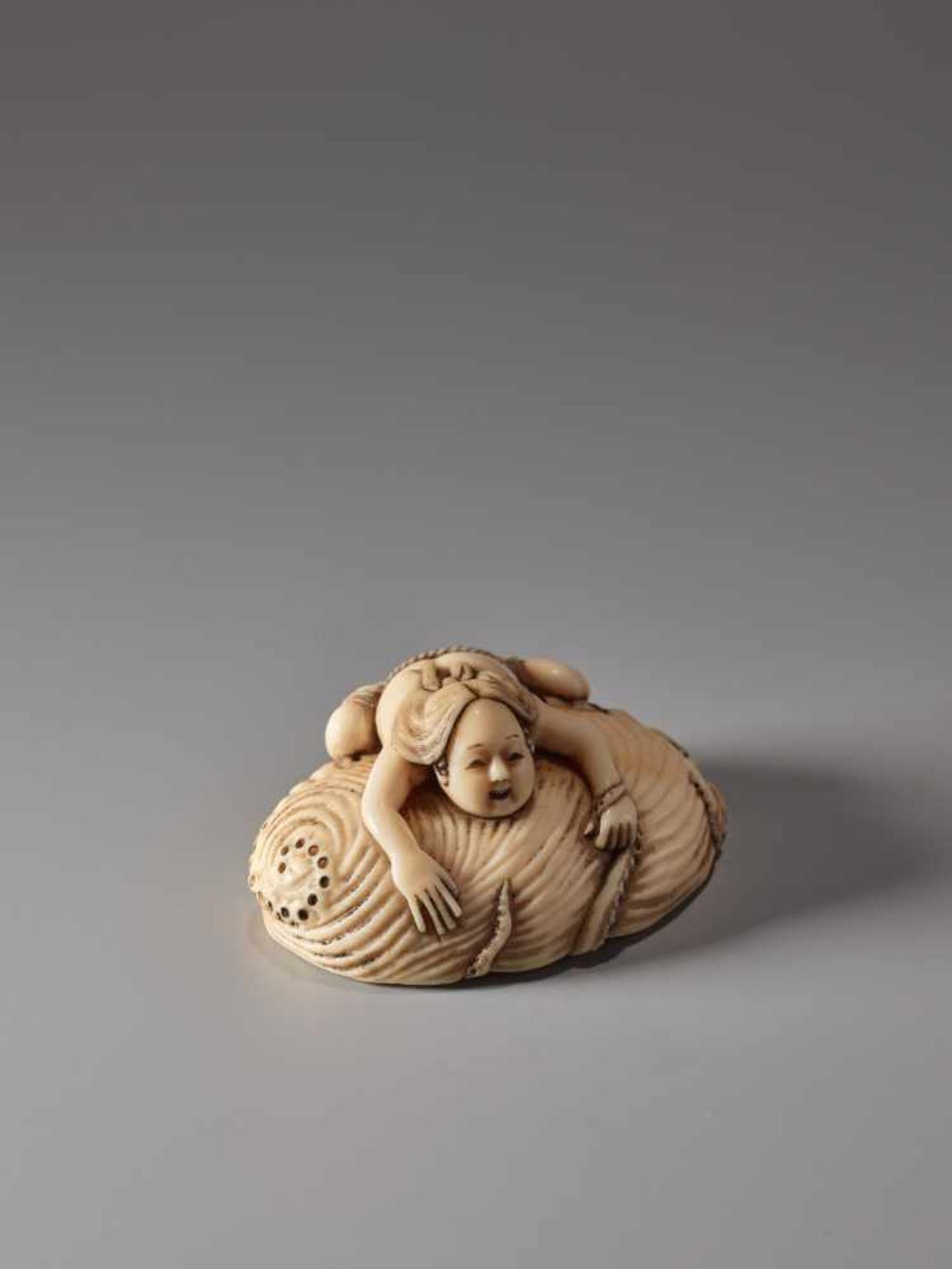 AN IVORY NETSUKE OF A FISHER GIRL AND OCTOPUS ON A GIANT AWABIIvory netsukeJapan19th century, Edo