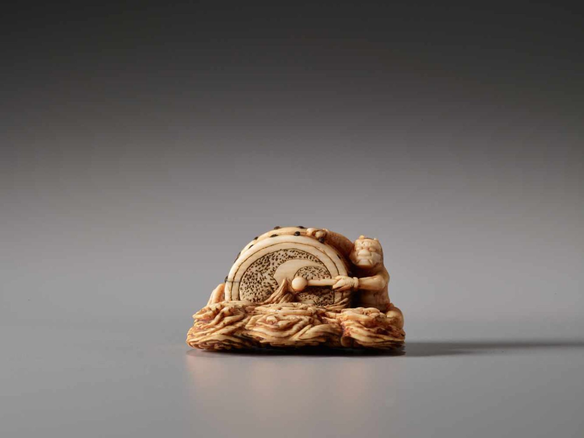 AN IVORY NETSUKE OF RAIJIN BEATING HIS DRUMIvory netsuke with horn inlaysJapanlate 18th to early