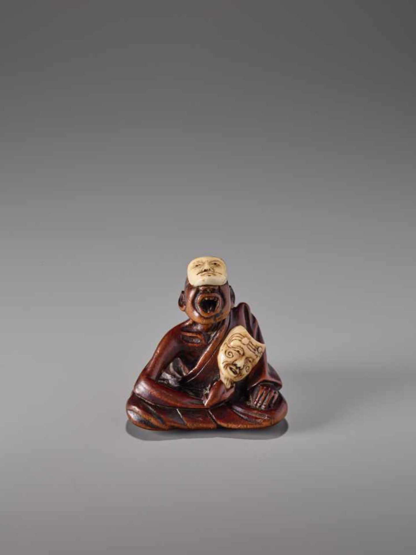 AN UNUSUAL WOOD AND IVORY NETSUKE OF A SNEEZER AS A NOH ACTOR BY HOKEIWood netsuke with