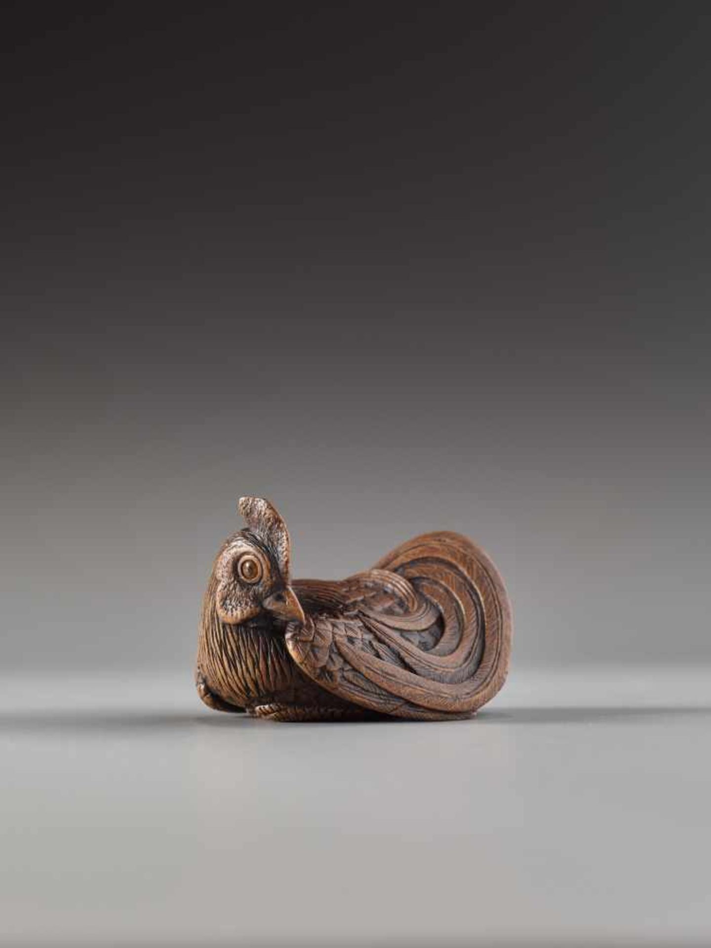 A FINE AND SMALL WOOD NETSUKE OF A RECUMBENT COCKEREL BY HOKYUDO ITSUMINWood netsukeJapan, Edomid-