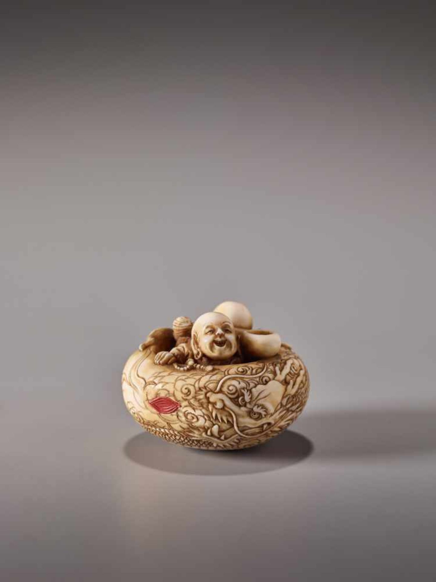 AN UNUSUAL IVORY MANJU NETSUKE WITH TWO MONKS IN AN ALMS BOWL BY SOKOKUIvory netsuke with lacquer