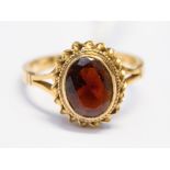 A 9ct gold and garnet dress ring, set with an oval garnet with rope edge surround, size J,