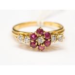 A ruby and diamond flower dress ring, with diamond claw set shoulders, in 18ct gold, size O 1/2,