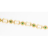 A yellow metal, (possibly 18ct) gold and emerald link bracelet,