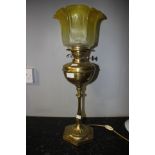 A brass oil lamp in the Arts and Crafts style, with yellow etched shade,