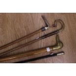 A swagger stick together with three walking sticks, one with brass ducks head handle,