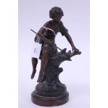 A spelter statuette mounted on a red veined marble plinth of a fisher boy sat on a tree trunk