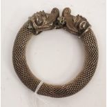 An Ethnic influence white metal bangle, formed from silver mesh culminating in two dragon heads,