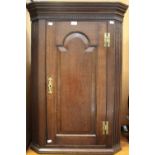 An 18th Century oak corner hanging cupboard, single arched panel door, fluted pilasters,