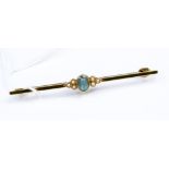 A 15ct stamped bar brooch set centrally with an oval aquamarine type stone set either side with