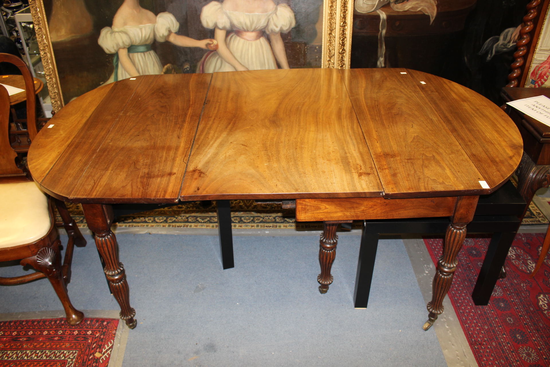 An early 19th Century mahogany extending dining table, fitted with an extra leaf,