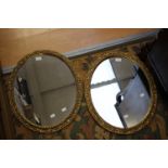 A pair of gilt wood 20th Century oval mirrors