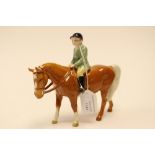 A Beswick model of a Palomino pony, with a green jacketed horse rider,