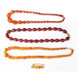 Three faceted amber type necklaces, comprising two cherry one orange coloured strands,