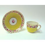 A Derby porcelain yellow ground tea cup and saucer, circa 1790, painted with bands of roses,