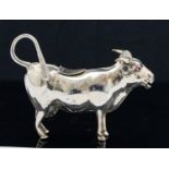 An Edwardian novelty silver cow creamer in the form of a cow, set with red cabouchon eyes,