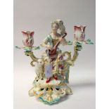 A Derby porcelain figural candelabrum, circa 1760-65, modelled as a shepherdess with lute and lamb,