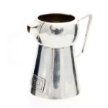 An Arts and Crafts silver jug, lobed conical form with angled handle and pinched square spout,